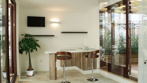 Una cocina moderna con una isla integrada, dos taburetes de bar, una planta en maceta y un televisor de pantalla plana montado en la pared.