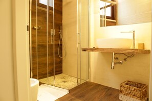 A modern bathroom with a glass-enclosed shower, a wooden floor, a white sink, and a small wicker basket. - Signuria Dimora Esclusiva (Lecce)