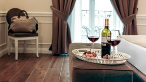 A dining area with a tray of cookies and wine glasses, a bottle of wine, and a handbag on a chair. - La Fontanina Suites (Naples)
