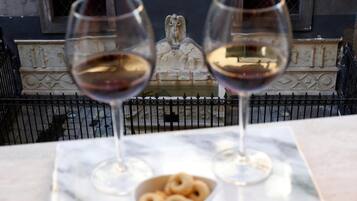 Two wine glasses on a marble table with a bowl of donuts in the foreground.