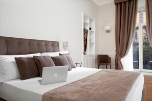 A hotel room with a bed, a laptop, a desk, and a chair. - La Fontanina Suites (Naples)