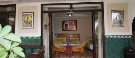 A room with a checkered floor, two beds with yellow pillows, a small table, and two chairs.