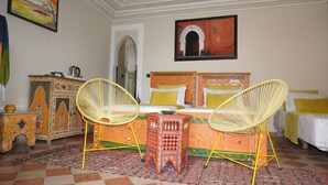A room with a bed, two wicker chairs, a small table, a cabinet, and a painting on the wall. - Riad Saida Atlas (Lalla Takarkoust)