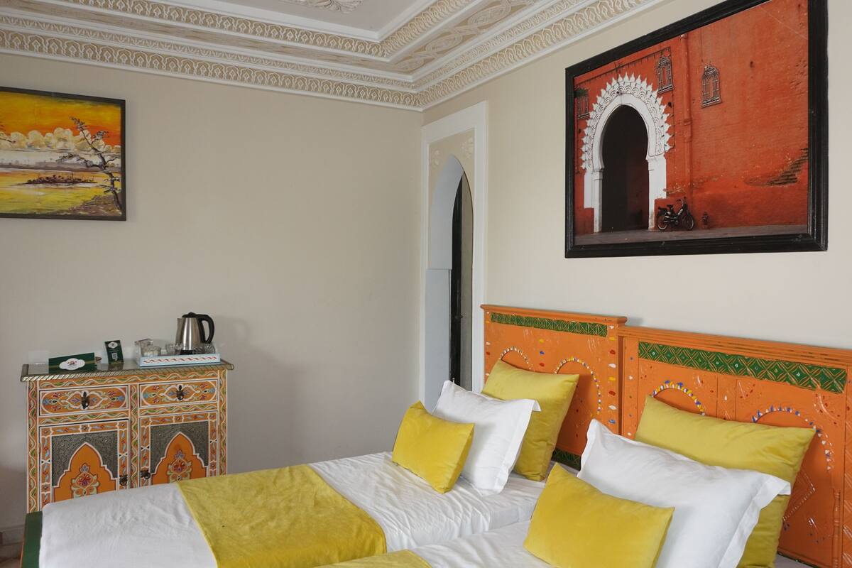 A hotel room with a bed, a dresser, and a painting on the wall.