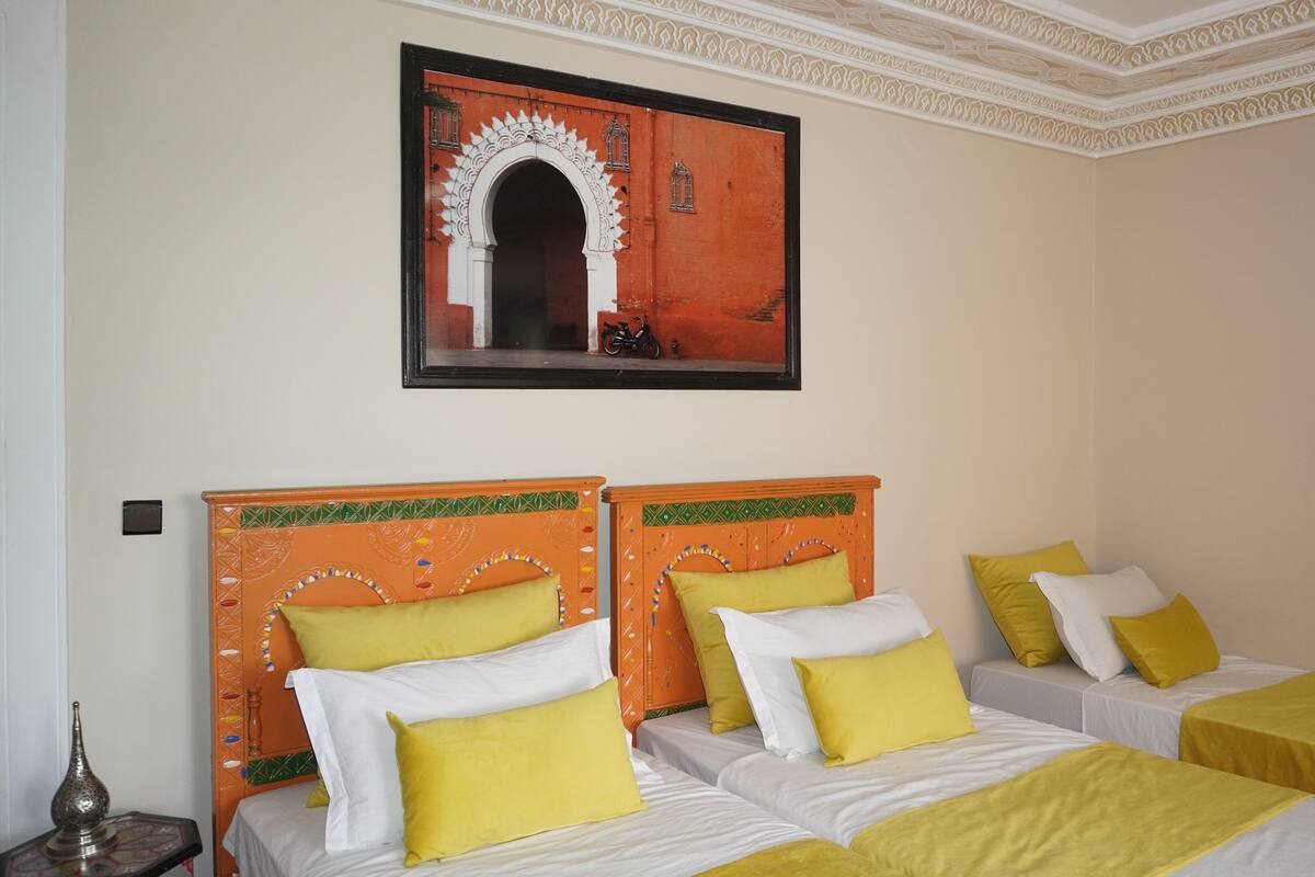 A hotel room with two beds, each with yellow and white bedding, and a decorative wall with a framed picture.