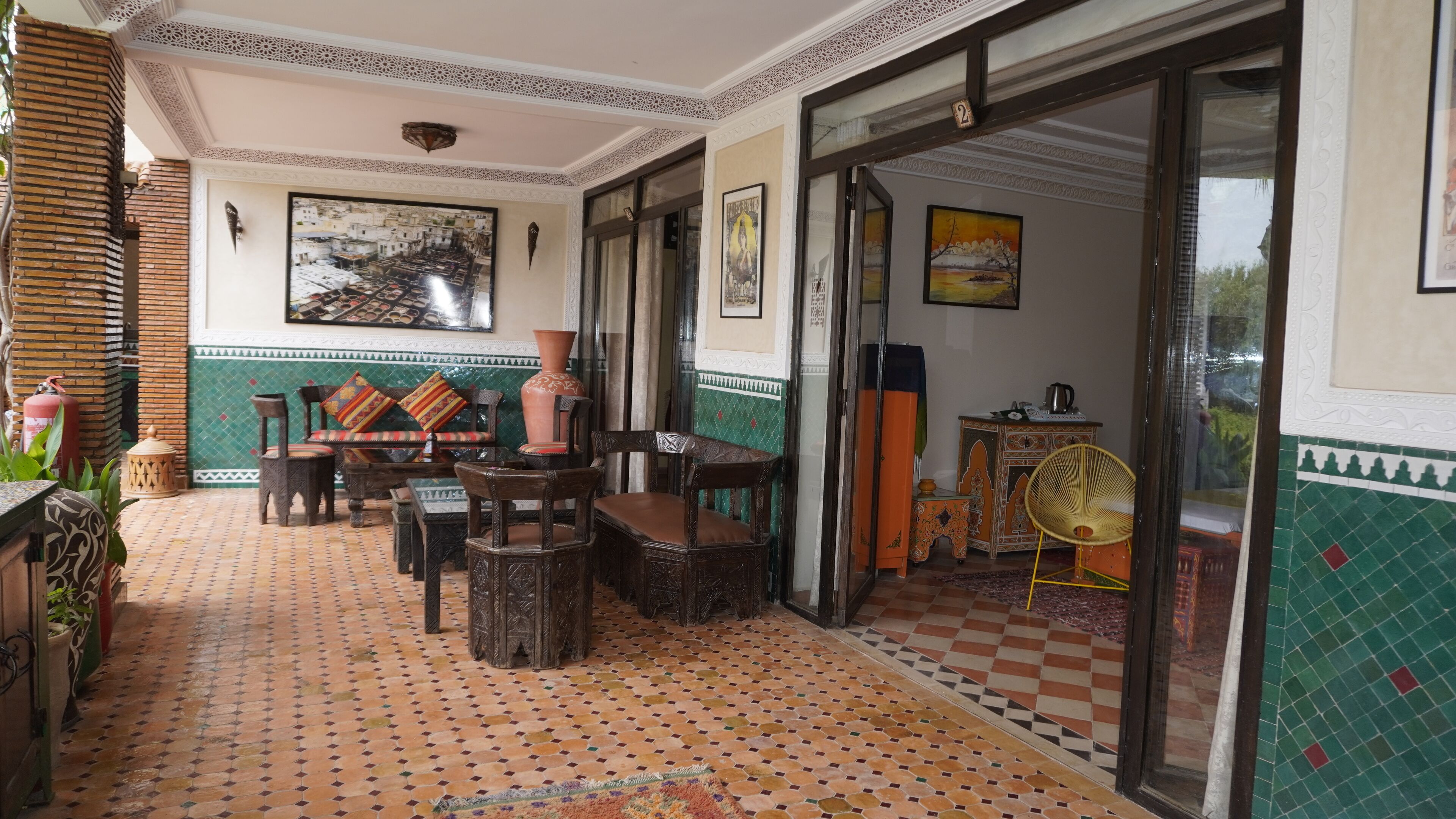 Um interior tradicional marroquino com piso de azulejos, móveis de madeira e elementos decorativos.