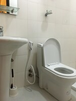 Un baño con lavamanos, inodoro y ducha blancos.