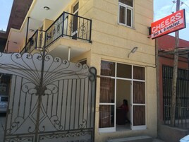 Un edificio con un letrero que dice "CHEERS Bed & Breakfast" y una puerta metálica decorativa.