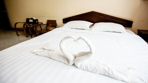 Una cama bien hecha con una toalla dispuesta en forma de corazón.