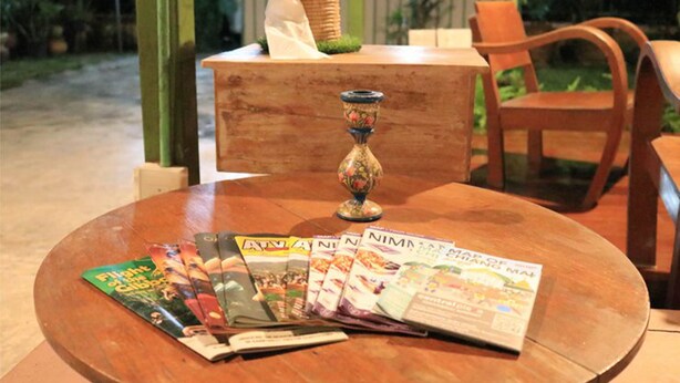 A round wooden table with a globe and several travel magazines.