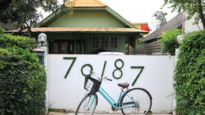 A turquoise bicycle parked in front of a white wall with the number 70187.