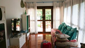 A room with a sofa, a television, a cabinet, and a suitcase.