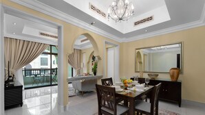 Une salle à manger spacieuse avec un plafond haut, des lustres et un grand miroir.