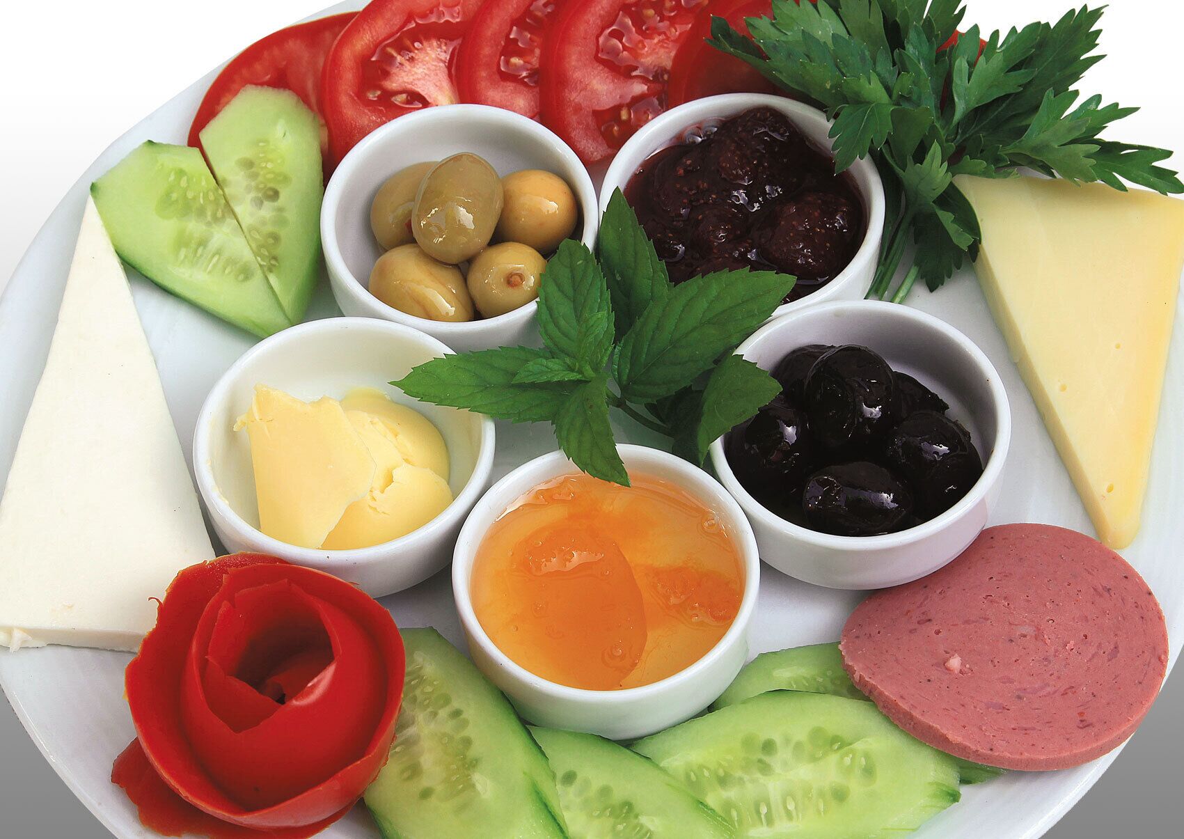Un plato con varios alimentos, incluyendo queso, aceitunas y verduras en rodajas.