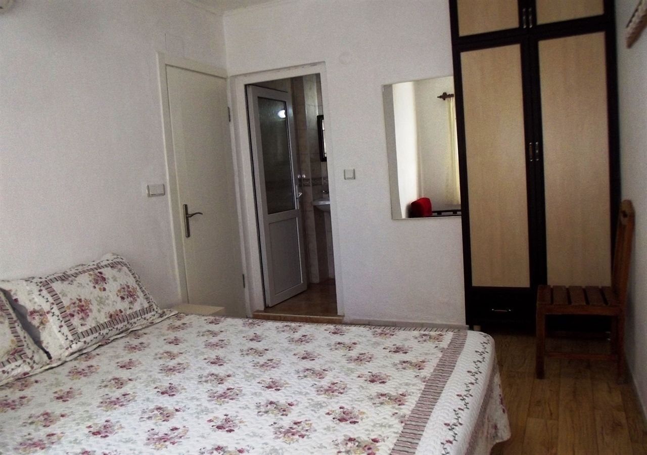A bedroom with a bed, a chair, a wardrobe, and a door leading to a bathroom.