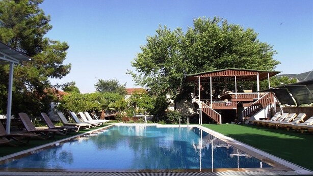 A swimming pool with lounge chairs and a covered area. - Dalyan Gurkan Apart Hotel (Ortaca)