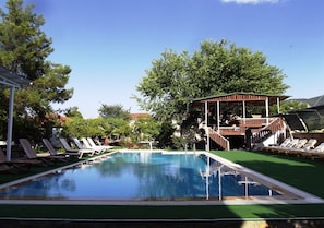 Une piscine avec des chaises longues et un espace abrité.