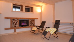 Una habitación acogedora con chimenea, dos sillones con cojines a rayas y techo de madera.