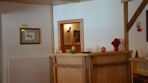 Un mostrador de recepción de madera con un cuadro enmarcado en la pared, un radiador y un pequeño árbol de Navidad.