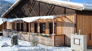 Una cabaña de madera con techo cubierto de nieve y un letrero que indica que es un hospedaje.