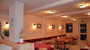 Un interior de madera con mesas y sillas, paredes y luces de techo de madera.