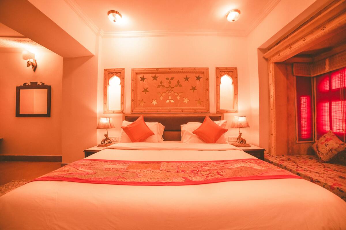 Een groot bed met een rode sprei, twee nachtkastjes met lampen en een muur met een stermotief.