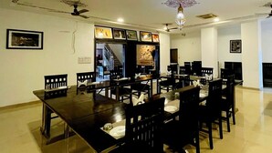 A dining area with a long table, multiple chairs, ceiling fans, and a chandelier. - Hotel Radhika Jaisalmer (Jaisalmer)