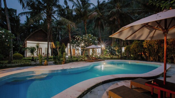 A swimming pool surrounded by palm trees and lounge chairs. - Crystal Bay Villa (Penida Island)