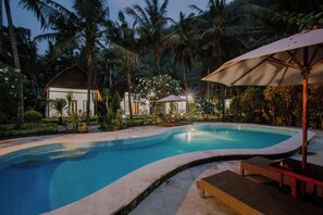 A swimming pool surrounded by palm trees and lounge chairs. - Crystal Bay Villa (Penida Island)