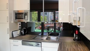 Een moderne keuken met een magnetron, broodrooster, spoelbak en koffiezetapparaat.