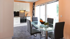 Een moderne keuken met witte kastjes, een glazen eettafel en zwarte stoelen.