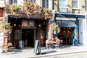 A hotel with a classic facade, outdoor seating, and flower boxes. - Fox and Anchor (London)