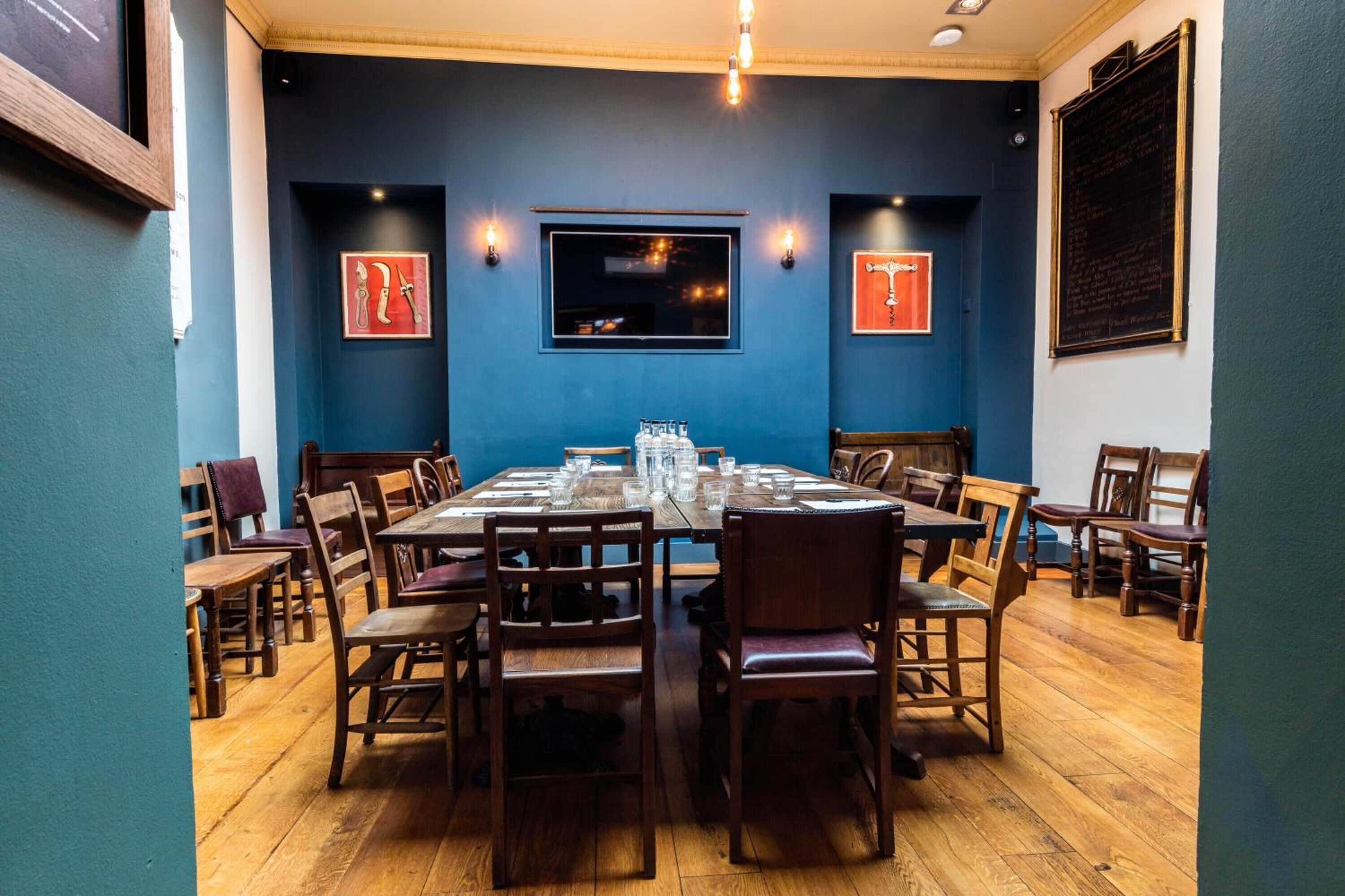 A dining area with a long wooden table set for six, surrounded by wooden chairs.