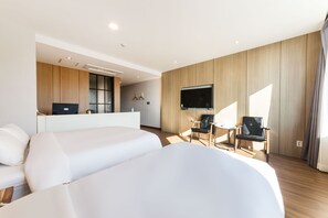 A modern hotel room with two beds, a desk, a TV, and a seating area with chairs. - Incheon Hotel Bluemarine (Incheon)