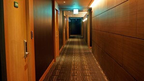 A hotel hallway with wooden doors, a patterned carpet, and a long corridor leading to a darkened room. - Incheon Hotel Bluemarine (Incheon)