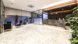 A hotel lobby with a marble floor, a reception desk, and several potted plants. - Incheon Hotel Bluemarine (Incheon)