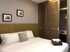 A hotel room with a bed, two framed pictures on the wall, and a wooden wardrobe with a control panel. - Telanai16 Lodge (Bandar Seri Begawan)