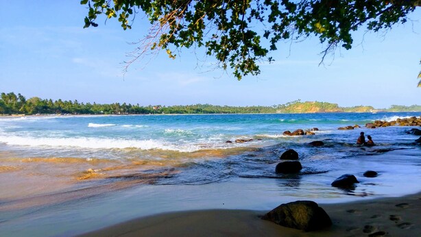 A beach with clear water, rocks, and footprints. - Paradise Beach House (Talalla)