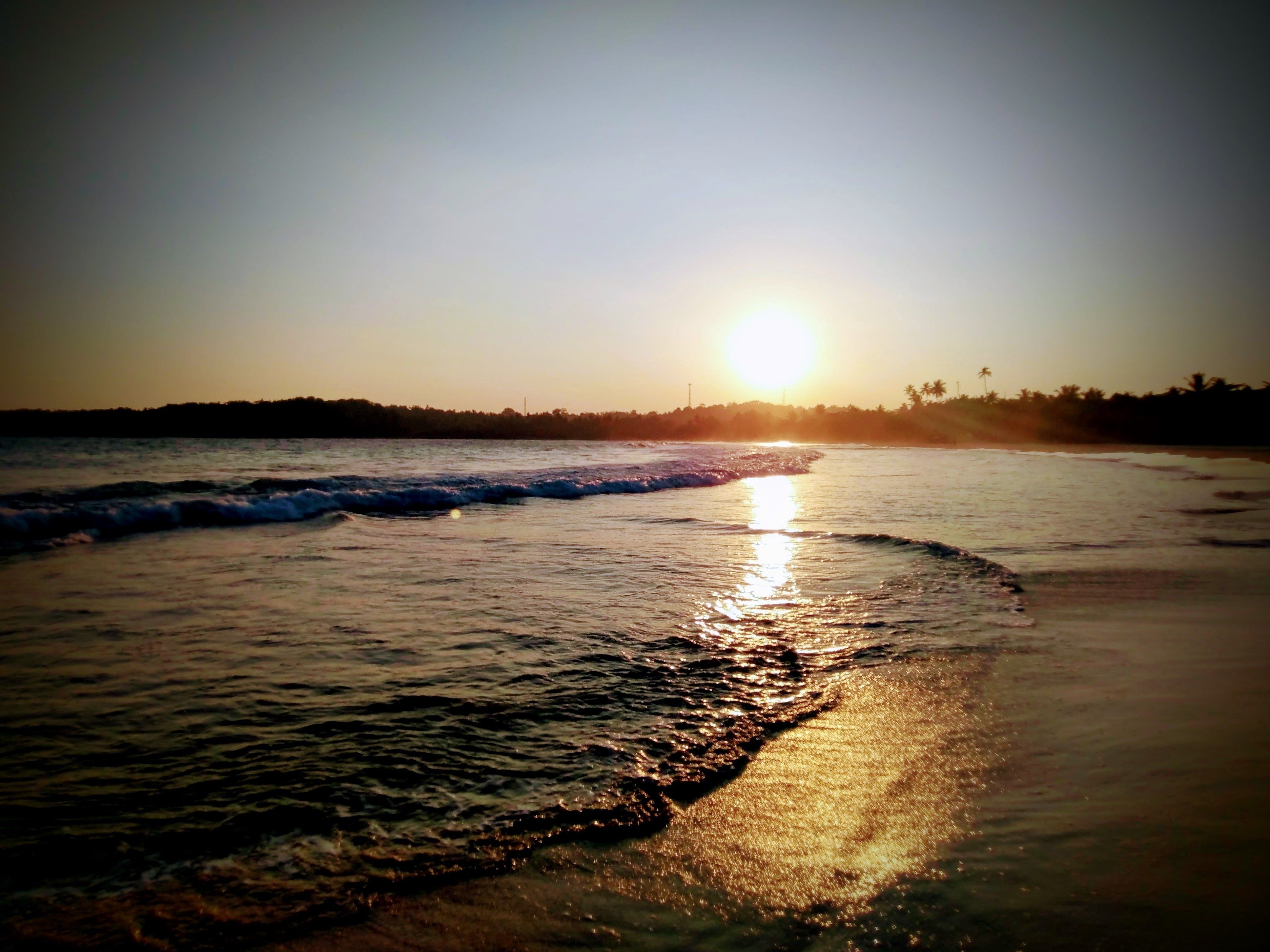 A beach scene with waves and a sunset.