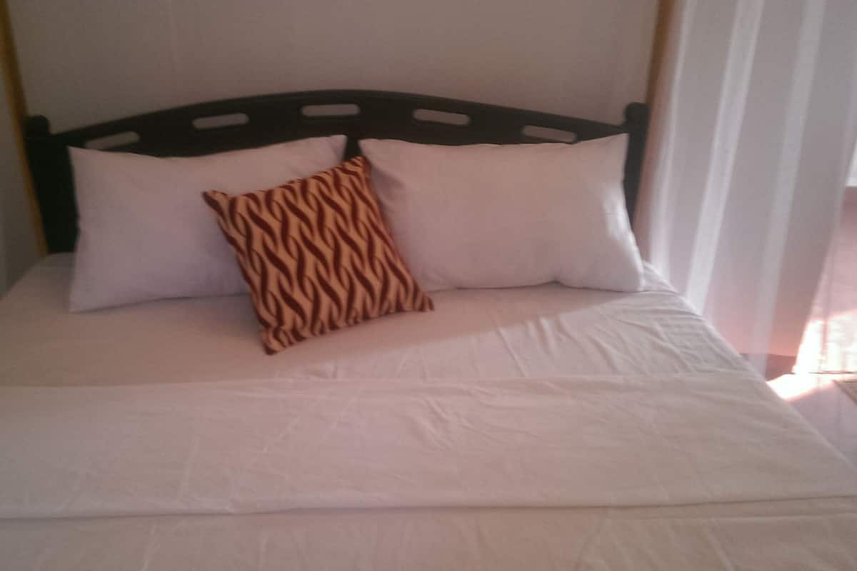 Una cama con ropa de cama blanca y una almohada estampada.