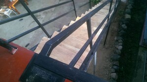 A staircase with metal railings and a wooden floor, leading to an upper level. - Paradise Beach House (Talalla)