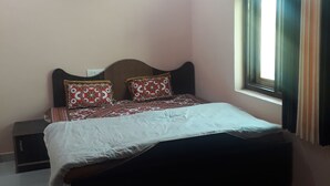 A bedroom with a bed, a nightstand, a ceiling fan, and a window with curtains. - Kukas Guest House (Amer)