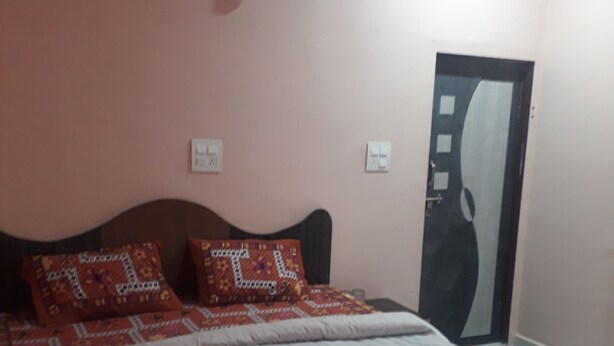 A bedroom with a bed, pillows, a wall clock, and a door. - Kukas Guest House (Amer)