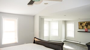 A bedroom with a bed, a ceiling fan, and large windows. - City's Escape (Pemberton)