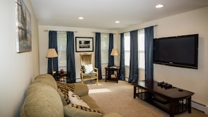 A living room with a sofa, armchair, television, and lamps. - City's Escape (Pemberton)