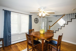 A dining area with a wooden table and chairs, a ceiling fan, and a staircase. - City's Escape (Pemberton)