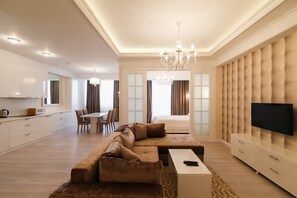 A modern living room with a sectional sofa, a flat-screen TV, and a dining area with a chandelier. - Homestay Apartments (Chisinau)