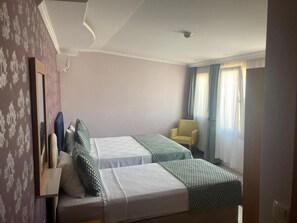 A hotel room with two beds, a chair, a mirror, and a window with curtains. - Otel Safran Palas (Foça)