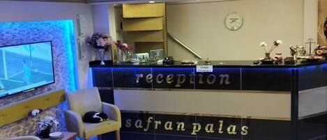 Un mostrador de recepción con un reloj, una pantalla de televisión y una alfombra decorativa.