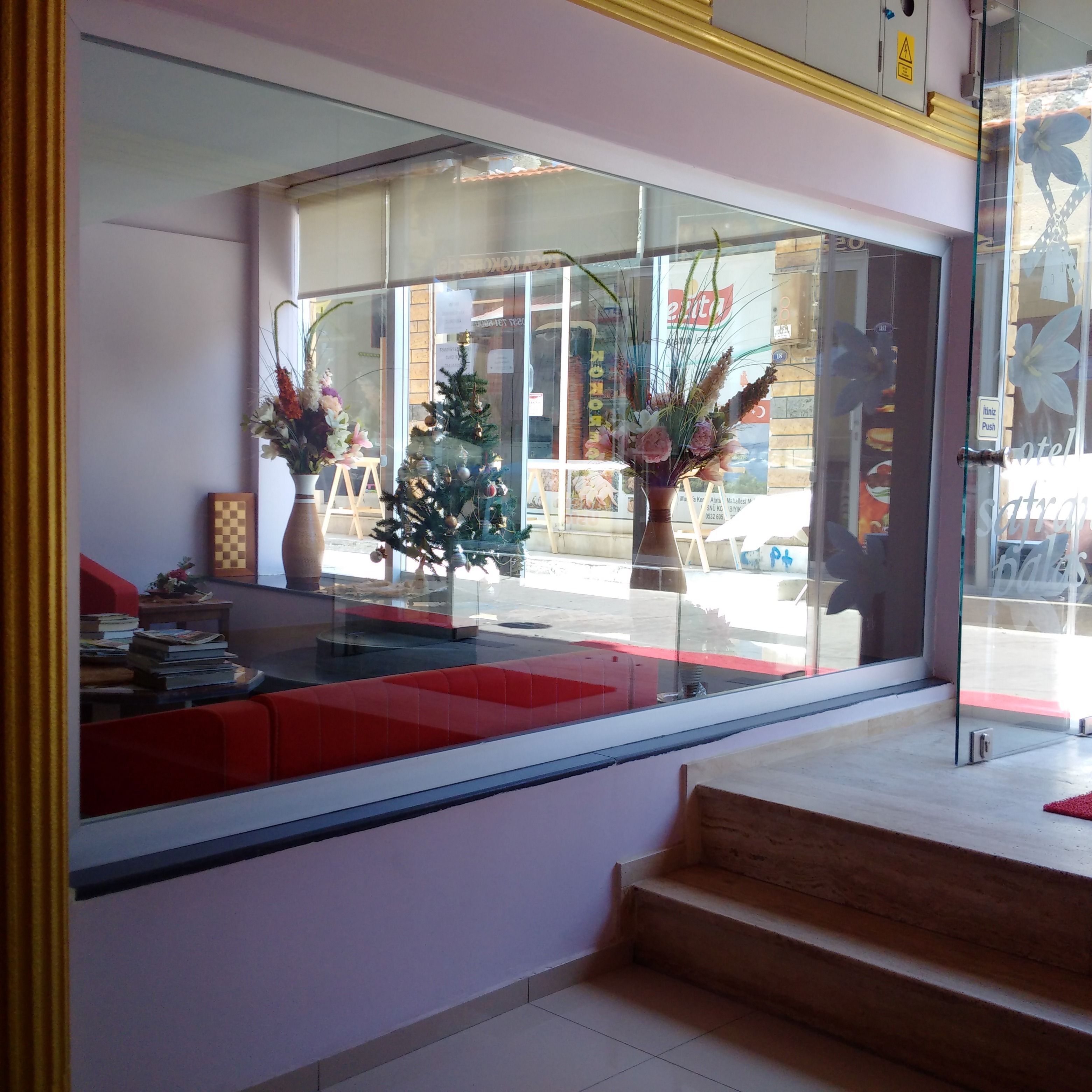 A hotel lobby with a glass partition, a small Christmas tree, and a staircase leading to the upper floor.